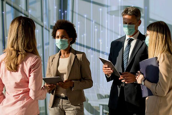 Four people wearing masks having a conversation in a lobby with an overlay of openblue graphics