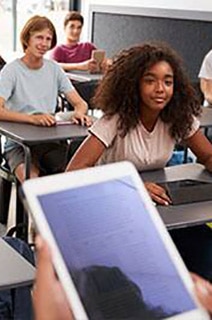 A teacher using a tablet to teach students in a classroom