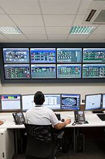 Three security officers monitoring cctv footage in a room