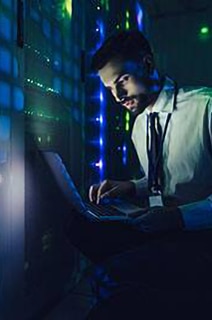 An engineer working on a laptop in a data center