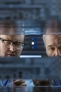 Two engineers inspecting data racks