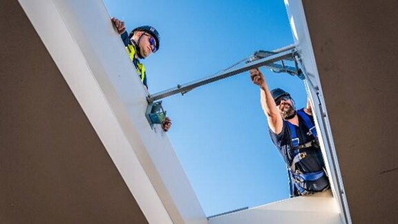 Engineers in safety suits inspecting a device installed in a building