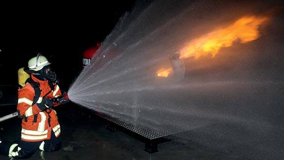 Firefighter using a water hose to extinguish a fire