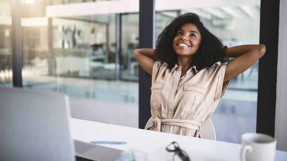 Woman sitting in an office chair in a relaxed position with her hands behind her head