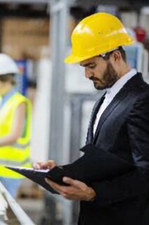 An engineer in safety helmet inspeting the work done in a factory