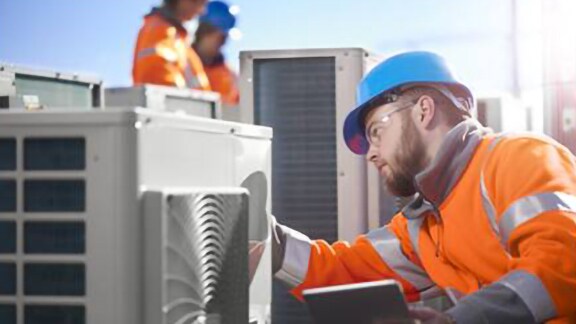 An engineer in safety suit and helmet inspecting a hvac device